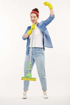 Pretty woman in work-wear holds a green mop and dances.の写真素材