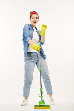 Pretty woman in work-wear holds a green mop and dances.の写真素材