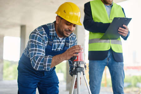 Two engineers on the construction use working equipment.