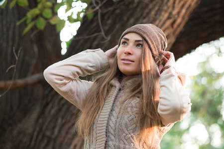Beautiful woman in a knitted garment wears a cap in the parkの写真素材