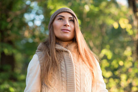 Beautiful woman in a knitted garment and cap in the parkの写真素材