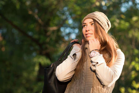 Beautiful woman in a knitted garment and cap in the parkの写真素材