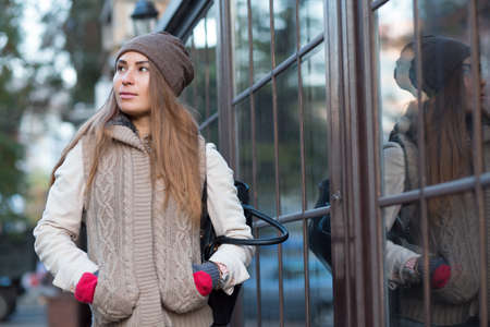 Beautiful woman in a knitted garment and cap walk in cityの写真素材