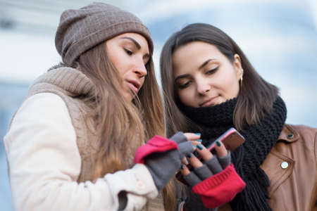 Girlfriend looking in smartphone in winter cityの写真素材