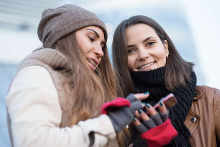 Girlfriend looking in smartphone in winter cityの写真素材