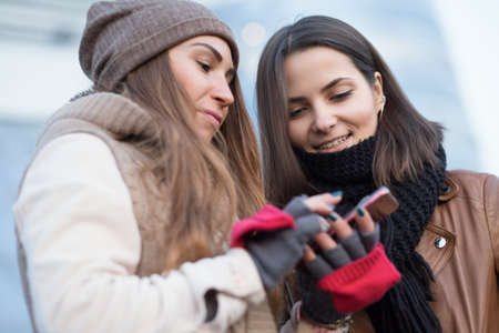 Girlfriend looking in smartphone in winter cityの写真素材