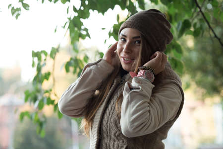 Beautiful woman in a knitted garment wears a hat in the parkの写真素材