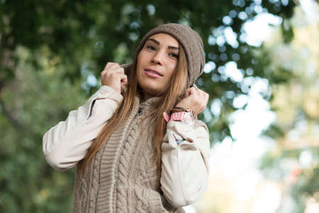 Beautiful woman in a knitted garment wears a hat in the parkの写真素材