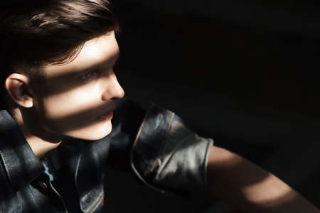 Stylish man in a denim jacket sits near blindsの写真素材
