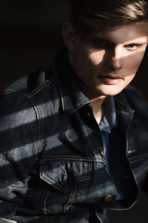Stylish man in a denim jacket sits near blindsの写真素材