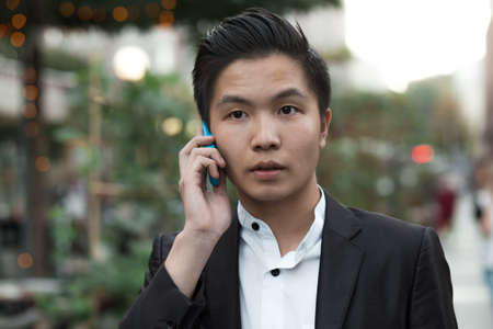 Chinese elegant purposeful businessman in avenue speak by phoneの写真素材