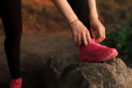 Pretty sportswoman tie shoelaces on a large stoneの写真素材