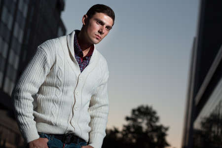Fashion photo of stylish man in white pullover. Building background.の写真素材
