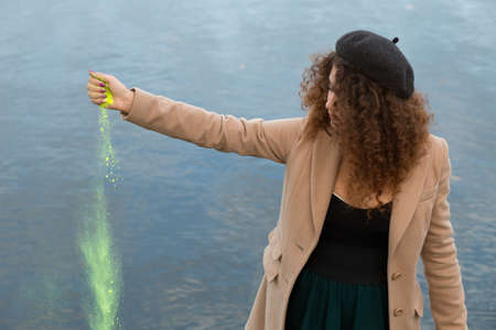 Woman throws bright paint near riverの写真素材