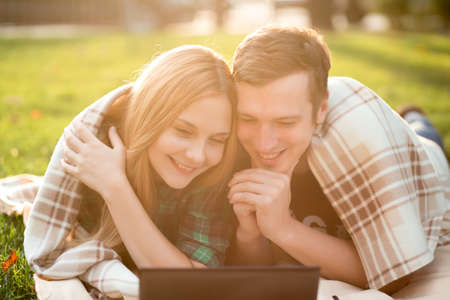 Young couple lying in the grass with a netbookの写真素材