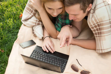 Young couple lying in the grass with a netbookの写真素材