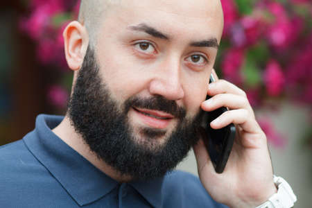 Bearded man talking on the phone mobile flowers backgroundの写真素材