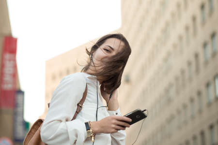 Pretty girl walking in city with phone. Hair on face.の写真素材