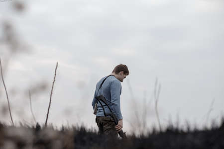Male hunter with rifle stand in spikelet field