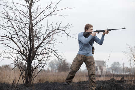 Huntsman shot with gun in open air on field. Autumn hunting.