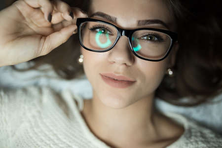 Cute woman in glasses lies on bedの写真素材