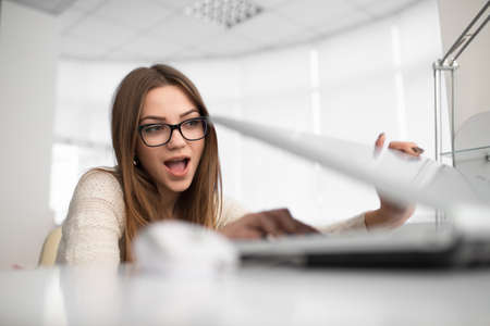 Young office woman worker. She sitting at her workstation and open notebook.