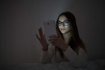 Woman using tablet in dark roomの写真素材