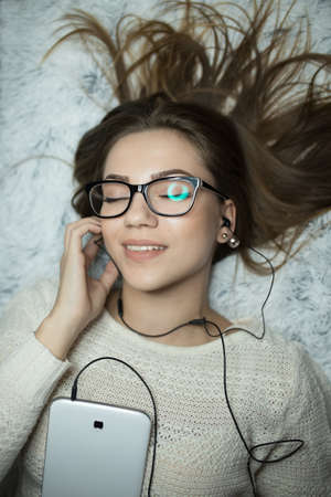 Sexy woman lying on bed listen music on tablet