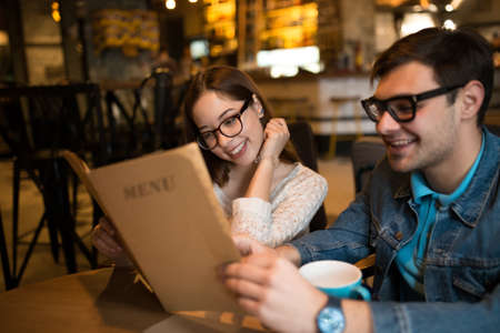 Young couple looking to the menu and choose a dish in cafeの写真素材