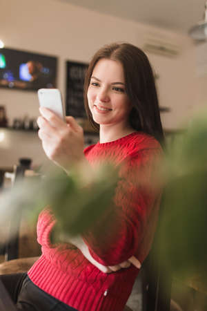 A young woman dials on her cellphone in cafeの写真素材