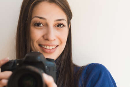 Brunette smiling woman photographer taking pictures with cameraの写真素材