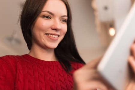 Woman in red pullover using her digital tabletの写真素材