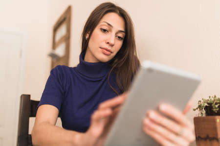 Woman in blue pullover using her digital tablet