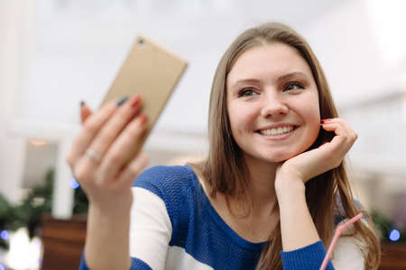Woman take self picture on her phone in light cafe