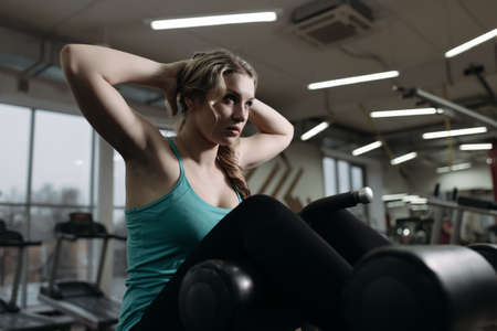 Beginner sportswoman doing press exercise in gymの写真素材