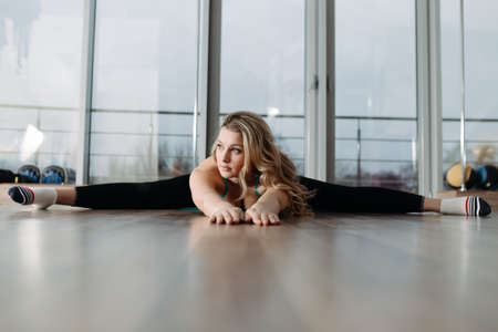 Woman doing stretching exercises on karemat in fitness centerの写真素材