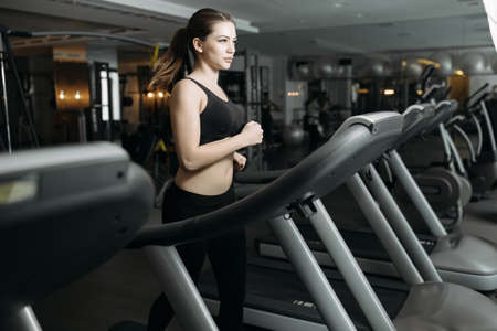 Adult sport woman running on treadmill in gymの写真素材