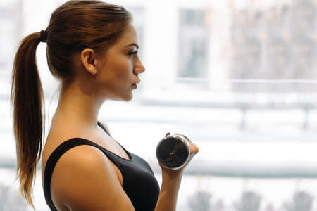 Beautiful woman lifting dumbbell in gym. She training biceps.の写真素材