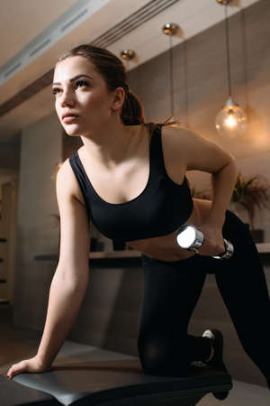 Beautiful woman lifting dumbbell at bench in gymの写真素材