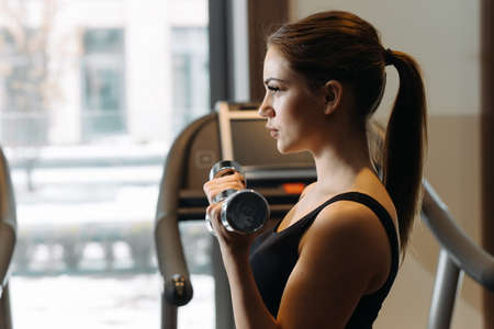 Young woman lifting dumbbell in gym. She training biceps.の写真素材