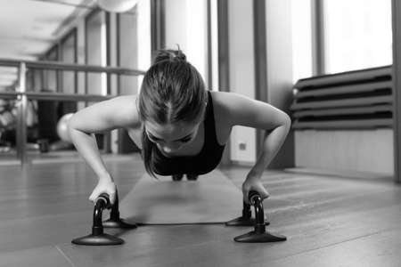 Woman doing push ups exercise. Powerful female exercising in health club.の写真素材