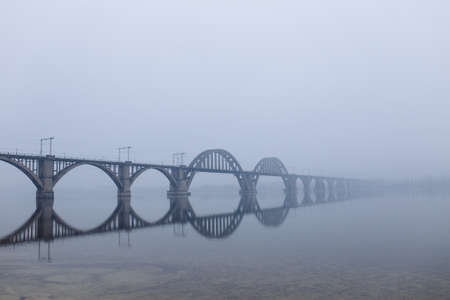 Bridge over river in fog winterの写真素材