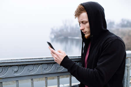 Sporty man using his mobile phone on bridgeの写真素材