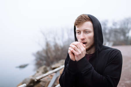 Caucasian man warming hands in cityの写真素材