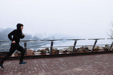 Sporty man jogging through rainy cityscape above the cityの写真素材