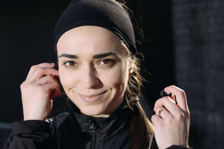 Beautiful athletic woman listen earphone and smile. Close-up portrait.の写真素材