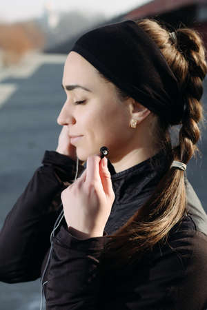 Beautiful woman listen music with closed eyes. Focus on earphone.の写真素材