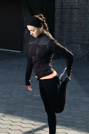 Young athletic woman doing stretching at urban location