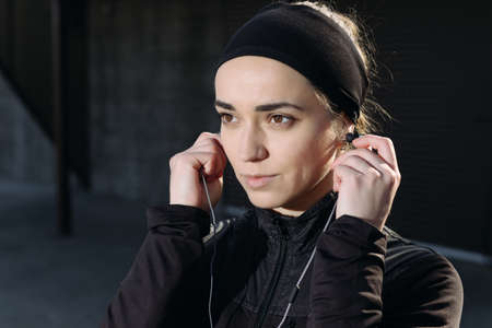 Beautiful athletic woman listen earphone. Close-up portrait.の写真素材