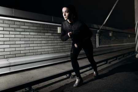 Woman running at nighttime on the roofの写真素材